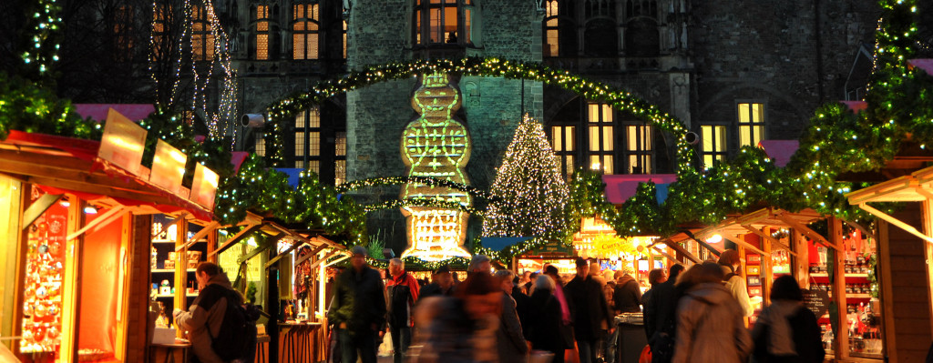 Der Aachener Weihnachtsmarkt mit seinen hell erleuchteten Buden auf dem Katschof. Im Hintergrund ist die Rückseite des Aachener Rathauses zu sehen.